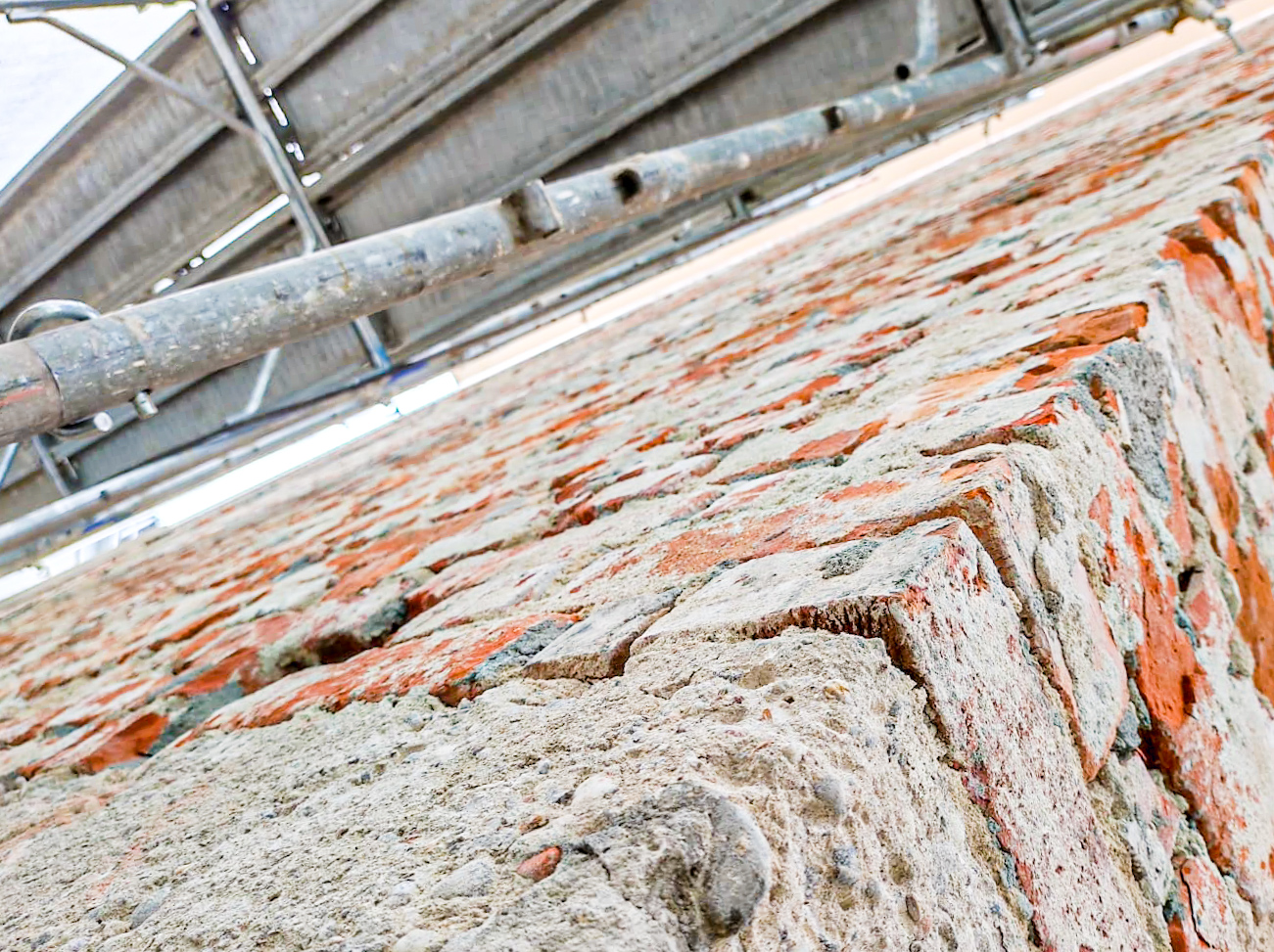 Persone lavorano al cantiere, mani che posano tavole e livellano una struttura con strumenti.